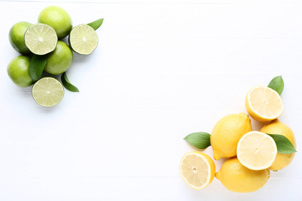 Lemons and limes with green leafs on white wooden table - Foto, Imagen