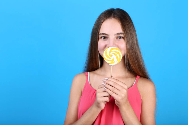 Young girl with lollipop on blue background - Foto, imagen