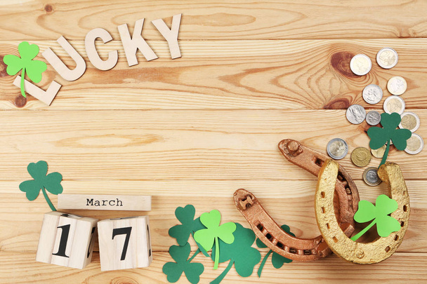 St.Patrick's Day. Golden horseshoes with clover leafs, wooden calendar and coins - Foto, Imagem