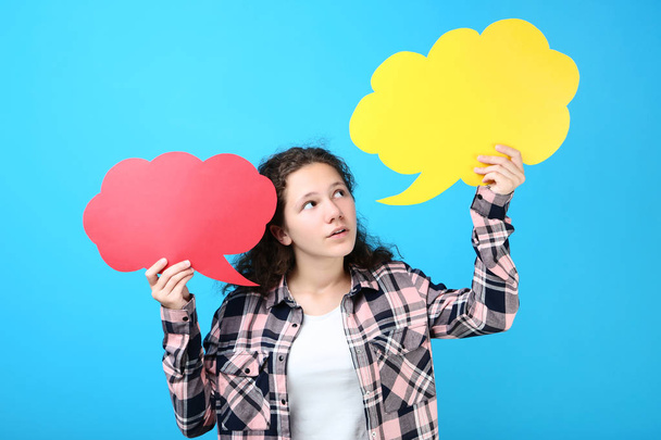 Young girl with speech bubbles on blue background - Φωτογραφία, εικόνα