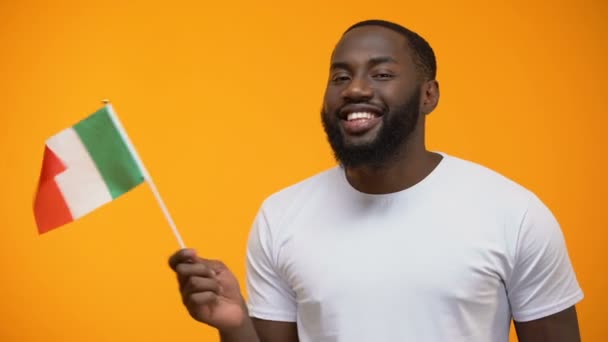 Smiling Afro-American man holding Italian flag, international friendship concept - Materiał filmowy, wideo