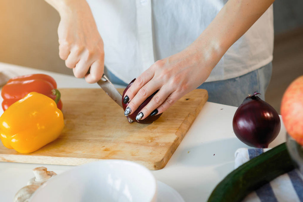mujer cortando cebolla en la cocina doméstica, enfoque selectivo
 - Foto, Imagen