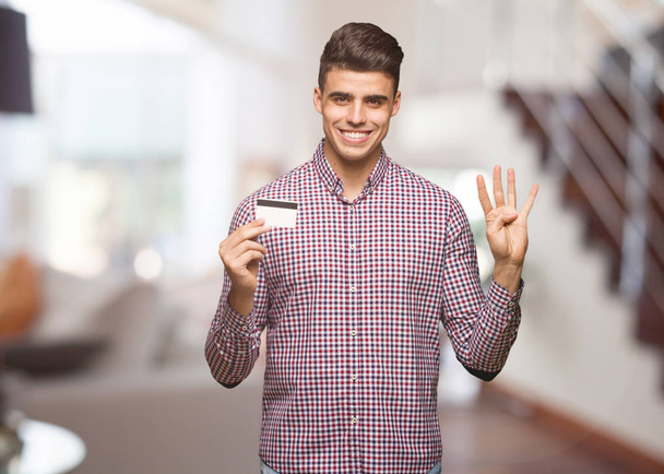 Młody człowiek posiadający karty kredytowej wyświetlone numer cztery - Zdjęcie, obraz