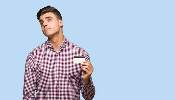 Jeune homme tenant une carte de crédit rêvant d'atteindre des objectifs et des buts
 - Photo, image