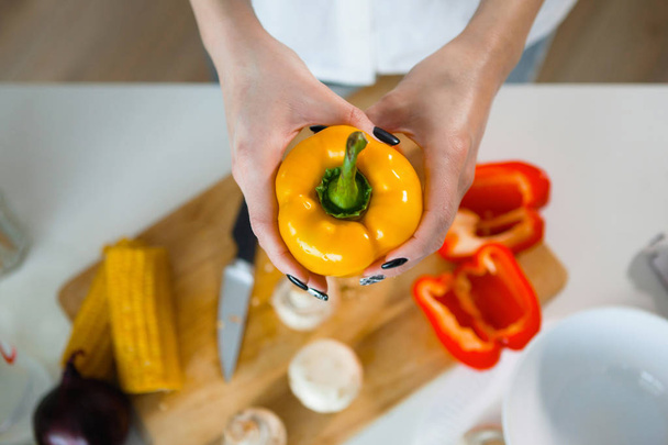 woman holding yellow pepper at domestic kitchen, selective focus - Photo, Image