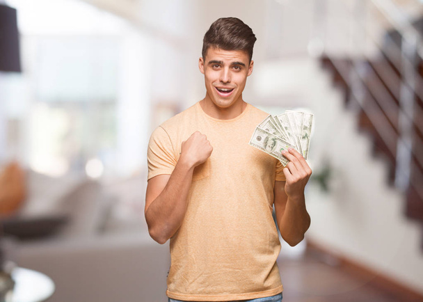 Jeune homme tenant des dollars surpris, se sent réussi et prospère
 - Photo, image