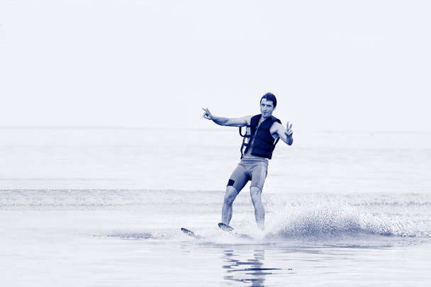 Szczęśliwy człowiek jazda na nartach wodnych i zabawy. Życia zdrowy styl życia i aktywność fizyczna. Sporty wodne robi w lecie na wakacje w Grecji. - Zdjęcie, obraz