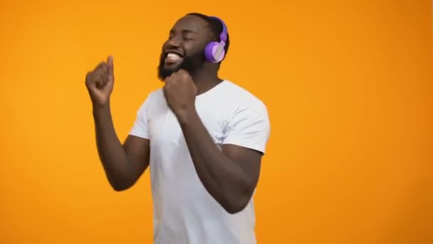 Afro-American man in headphones dancing actively performing winner moves closeup - Felvétel, videó
