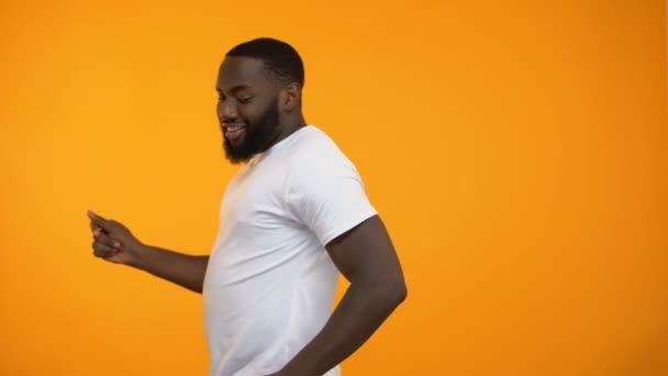 Joyful man moving back and forth against yellow background, having fun, close-up - Materiał filmowy, wideo