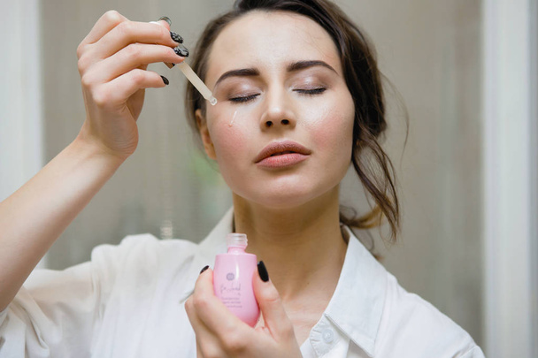 attractive woman moisturizing skin, focus on foreground - Foto, Imagen