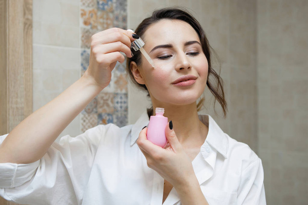 attractive woman moisturizing skin, focus on foreground - Фото, зображення