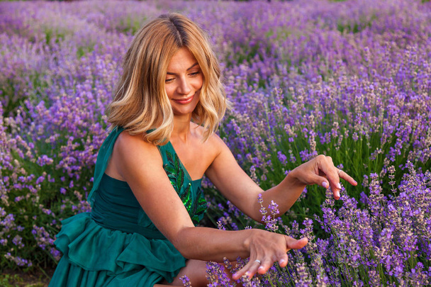 Beautiful girl in a green dress posing on a lavender field - Foto, afbeelding