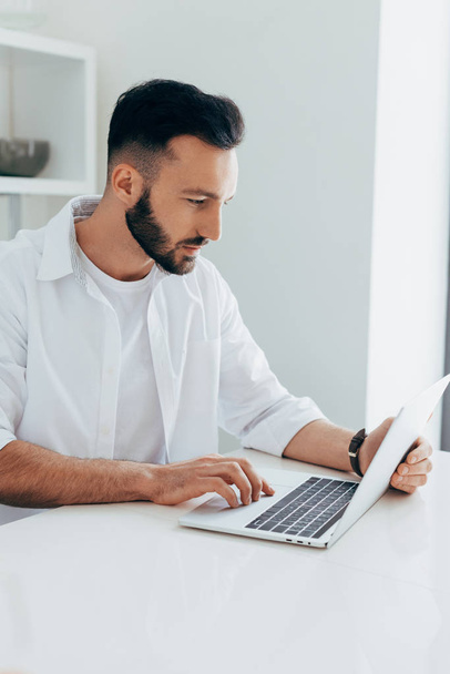 Concentrated brunette man in white shirt using laptop - Foto, Imagem