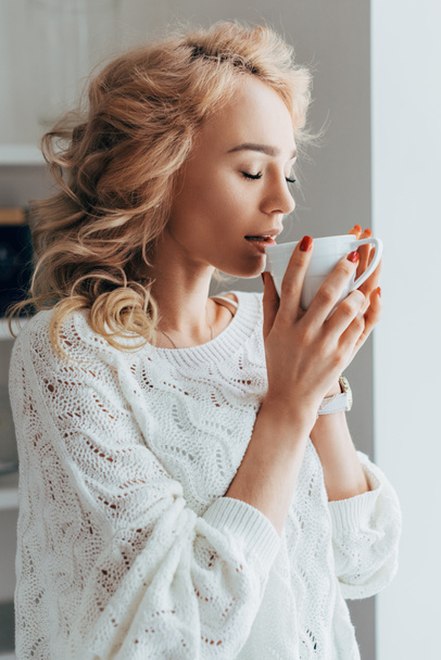 Relaxed curly girl drinking coffee with closed eyes - Фото, изображение