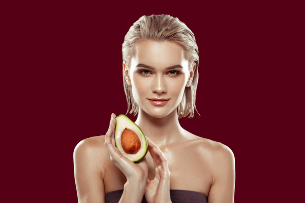 Model with bob cut having nice makeup while posing with avocado - Photo, Image