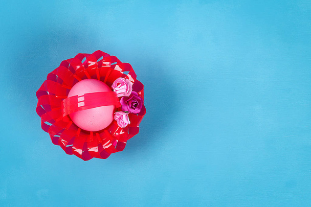 Panier d'œufs de Pâques bricolage en tasse en plastique rouge décoré avec des fleurs artificielles fond bleu. Idée cadeau, décor Printemps, Pâques. Pas à pas. Vue de dessus. Processus enfant enfants artisanat de Pâques. recyclage
 - Photo, image