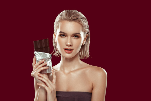 Slim appealing model holding bar of dark chocolate - Foto, afbeelding