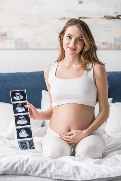 Lächelnde schwangere Frau zeigt Ultraschalluntersuchungen  - Foto, Bild