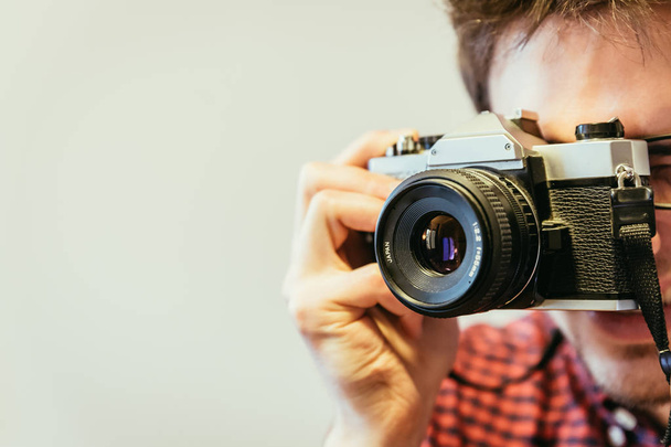 Jeune homme en chemise à carreaux rouge-bleu prend une photo avec un appareil photo vintage, style rétro
 - Photo, image
