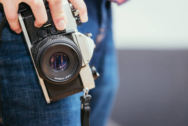 Man is holding a vintage camera in his hand, jeans and shirt - Foto, Imagem