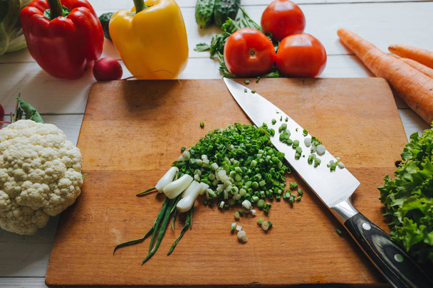 Cooking salad still. Knife and cut fresh green onion on chopping board. Vegetables border frame. - Foto, Imagem