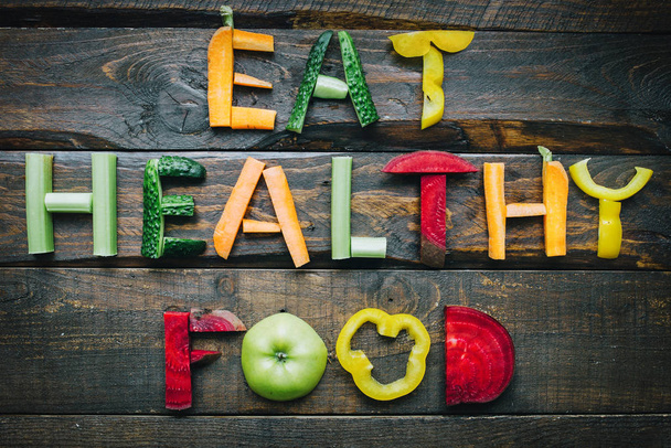 Eat healthy food fresh vegetables flat lay lettering on dark wooden table top view. Nutrition organic meal ingredients concept. Nice cooking postcard, poster, banner. - Photo, Image