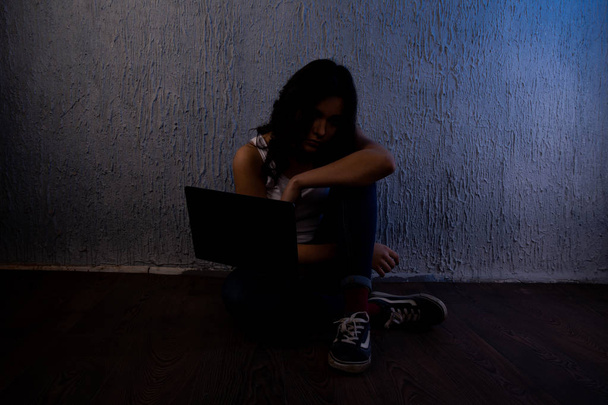 sad and scared female teenager with computer laptop suffering cyberbullying and harassment being online feeling desperate and humiliated in cyber bullying - Photo, Image