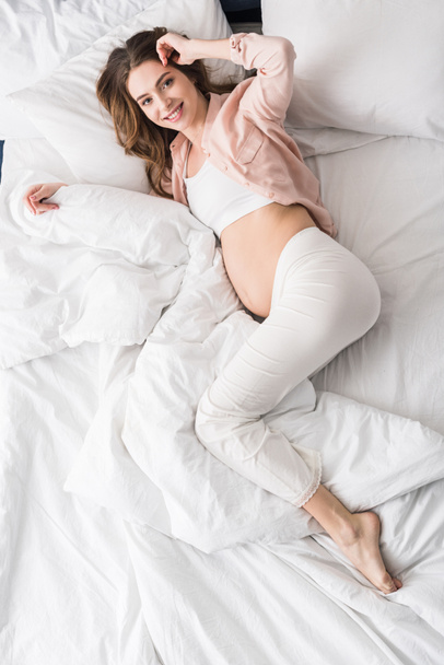 Felülnézet elégedett terhes nő feküdt az ágyban, mosoly - Fotó, kép