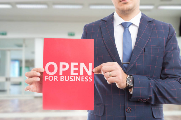Hombre vistiendo traje y corbata presentando letrero de papel rojo con texto abierto para negocios
 - Foto, imagen