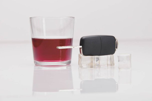 Un bicchierino di whisky e un mazzo di chiavi della macchina su un bianco
 - Foto, immagini
