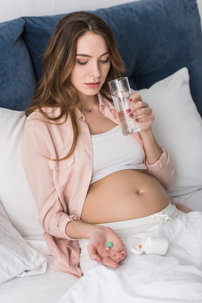 Femme enceinte tenant des pilules et de l'eau potable
 - Photo, image