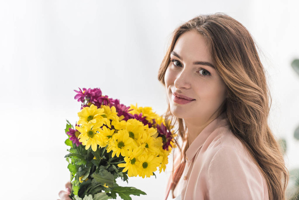 Attractive young woman with flowers looking at camera - Fotografie, Obrázek