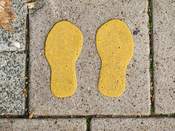 Желтые отпечатки обуви, раскрашенные на тротуарной плитке, предназначены для целей
. - Фото, изображение