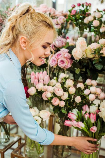 mooie lachende vrouw kiezen van bloemen in de bloemenwinkel - Foto, afbeelding