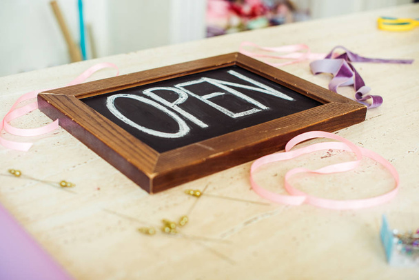 selective focus of wooden chalk board with 'open' lettering on table with ribbons - Photo, Image