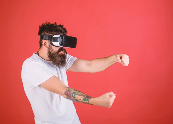 Man with beard in VR glasses driving car, red background. Virtual racing concept. Guy play racing game in VR. Hipster on aggressive face driving car on high speed in virtual reality - Foto, Imagem
