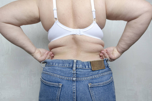Вид ззаду на верхню частину муфти жінки, на спині.Жінка показує свою жирну форму.Концепція здорового способу життя
 - Фото, зображення