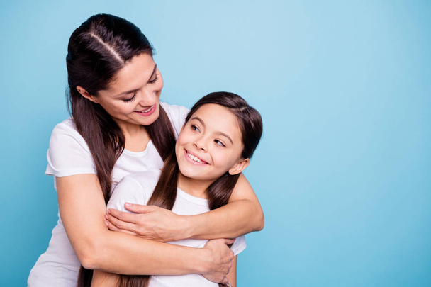 Close up photo pretty two people brown haired mum small little daughter missed glad see each other stand hugging piggy back nice rejoice wearing white t-shirts isolated on bright blue background - Fotografie, Obrázek