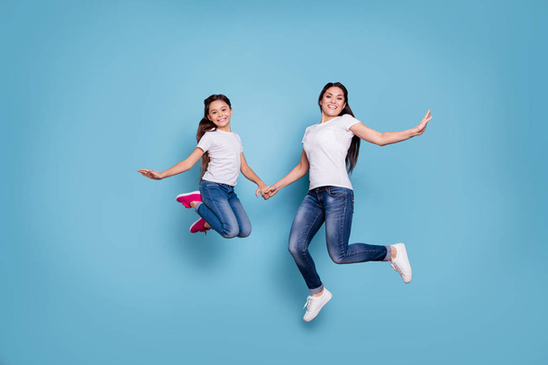Full length body size view of two nice cute lovely attractive cheerful funny slim sporty people in white t-shirt holding hands having fun rejoicing isolated over blue pastel background - Foto, Bild