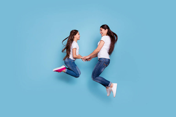 Full length body size profile side view of two nice adorable lovely attractive cheerful funny slim sporty people in white t-shirt holding hands having fun isolated over blue pastel background - Foto, afbeelding