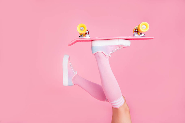 Cropped close up photo maigre idéal parfait elle ses jambes de dame soulevé tenant skateboard pousser avec un orteil roulant dans l'air passionné isolé rose fond
 - Photo, image