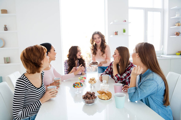 Close up portrait amazing beautiful she her diversity ladies sit round big white table in bright kitchen hold cups hot beverage try new recipe cakes girls day night holiday indoors - Photo, image