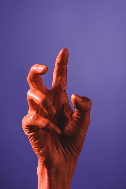 cropped view of woman gesturing with coral colored hand on violet background, color of 2019 concept - Photo, Image