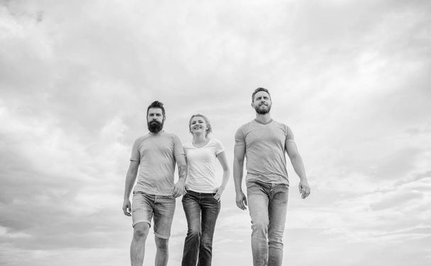 United threesome true friends. Men and woman walks dramatic cloudy sky background. True friendship grow with destiny obstacles. United group purposefully moves forward. Friendship tested for years - Photo, image