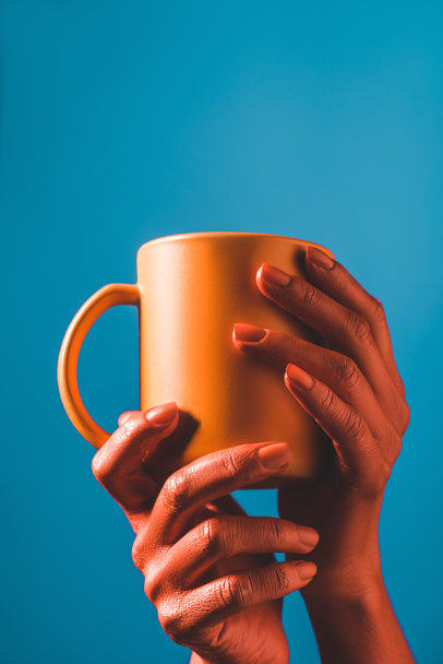 vista cortada de coral colorido mãos femininas com copo de café coral no fundo azul, cor do conceito 2019
 - Foto, Imagem