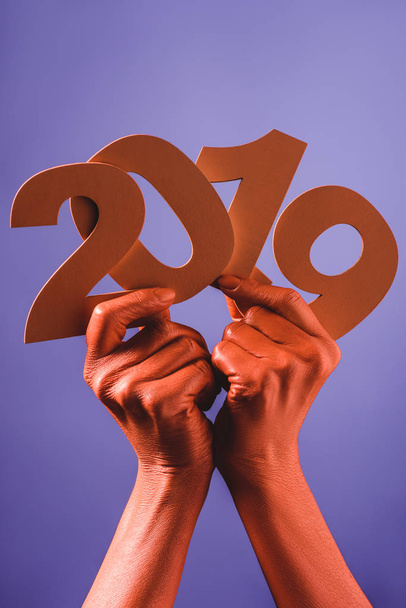 Teilansicht der korallenfarbenen weiblichen Hände mit Papierschnitt 2019 Zahlen auf blauem Hintergrund, Farbe 2019 Konzept - Foto, Bild