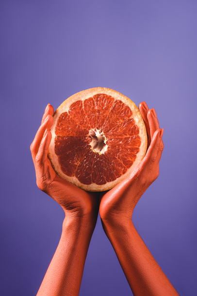részleges rálátással rendelkező nő vágott grapefruit, korall színű kézzel a kék háttér, szín, 2019 fogalom - Fotó, kép