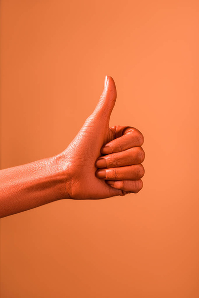 cropped view of woman showing thumb up on coral background, color of 2019 concept - Fotó, kép