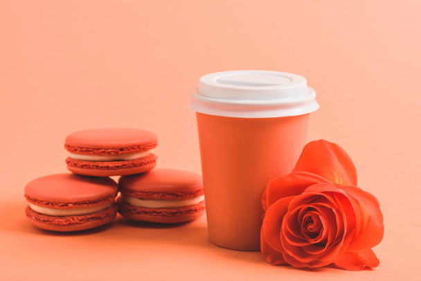 delicious macarons and paper cup on coral background, color of 2019 concept - Photo, Image