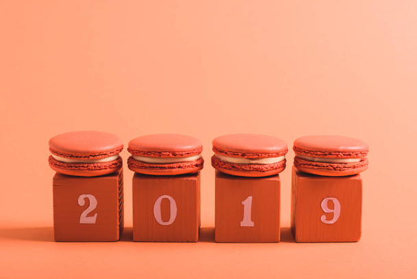 coral cubes with 2019 numbers and macarons on coral background, color of 2019 concept - Foto, Imagen